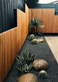 an outdoor area with rocks, plants and wood slats on the side of it