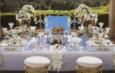 the table is set with white flowers and gold chairs for an elegant dinner party or reception