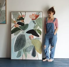 a woman standing next to a painting on the wall