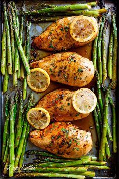 chicken with lemons and asparagus on a baking sheet