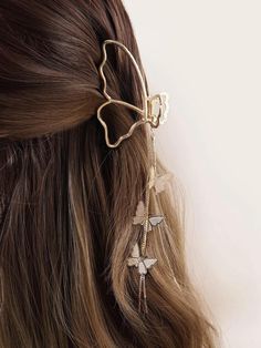 a woman with long hair wearing a gold butterfly hair clip