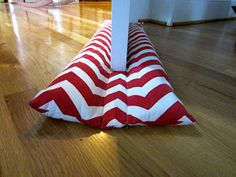 a red and white striped pillow sitting on top of a wooden floor