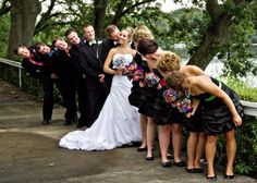 a group of people standing around each other in front of trees and water at a wedding