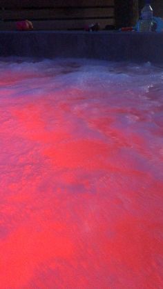 a hot tub filled with pink water and people in the background