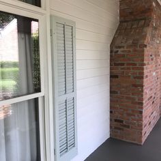 a brick chimney on the side of a house next to a window with shutters