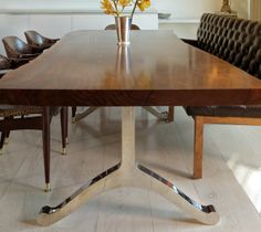 a large wooden table sitting in the middle of a room with leather chairs around it