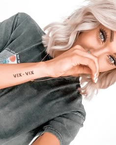 a woman with a tattoo on her arm posing for a photo in front of a white background