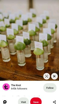 small glasses filled with green fruit on top of a wooden table next to each other