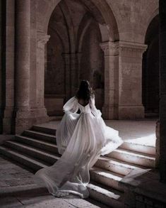 a woman in a white dress is walking up some stairs