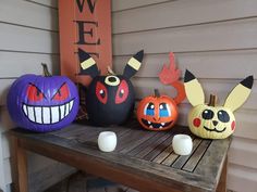 pumpkins decorated with pokemon and pikachu faces sit on a wooden table in front of a welcome sign