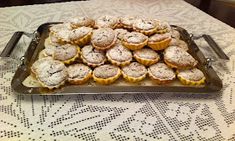 a tray full of pastries sitting on top of a white tablecloth covered table