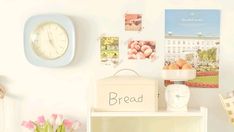 there is a clock on the wall next to a shelf with pictures and flowers in it