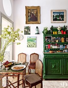 an image of a dining room with green furniture and pictures on the wall above it