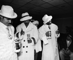 three men in white coats and hats are holding cups while one man is wearing a hat