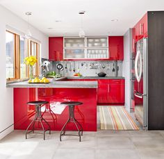 a kitchen with red cabinets and stools