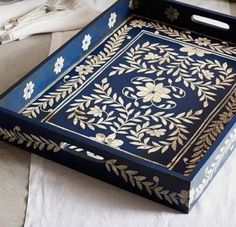 a blue and gold tray on a white table cloth with silverware in the background