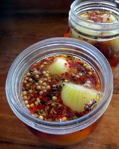 two jars filled with food sitting on top of a wooden table