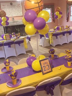 the table is set up with purple and yellow decorations for a basketball themed birthday party