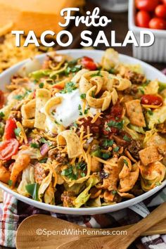 a white bowl filled with taco salad and tortilla chips on the side