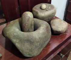 three large rocks sitting on top of a wooden table next to a red cabinet and door