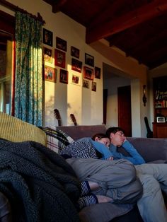 two people laying on a couch in a living room