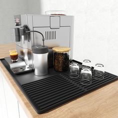 an espresso machine sitting on top of a counter next to glasses and coffee