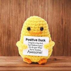 a yellow stuffed chicken holding a sign that says positive duck i may be tiny duck but i believe you can't stop trying