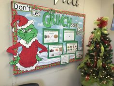 a bulletin board with an image of the grinch on it next to a christmas tree