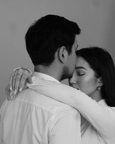 black and white photograph of a man kissing a woman's head with his arm around her neck