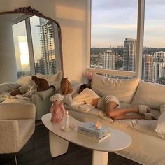 a person laying on a couch in front of a window with a cat and dog