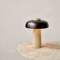 a table lamp sitting on top of a white marble slab with a black metal base