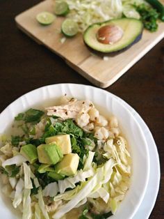 a white plate topped with salad next to an avocado on a cutting board