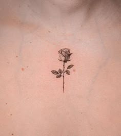 a rose tattoo on the back of a woman's chest is shown in black ink