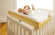 a baby laying on top of a white crib