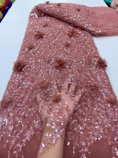 someone's hand on the ground covered in sequins next to a pink blanket