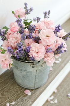 pink and purple flowers are in an old bucket