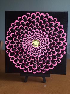 a pink and black art piece sitting on top of a wooden table