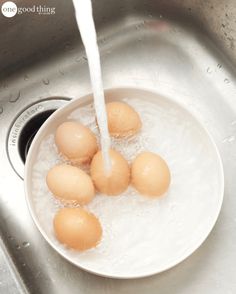 eggs are being washed in a sink with water pouring out of the faucet