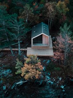 an aerial view of a small cabin in the middle of a forest with trees surrounding it