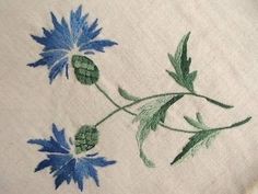 blue flowers on white linen with green leaves