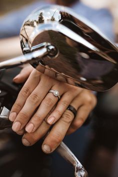 a close up of a person's hand with a wedding ring on top of a motorcycle