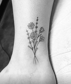 a flower tattoo on the ankle is shown in black and white, with daisies