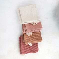 four towels stacked on top of each other in different colors and patterns, with one folded up to the side