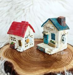 two small houses sitting on top of a piece of wood next to eachother