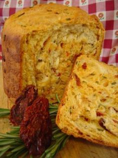 a loaf of bread sitting on top of a cutting board next to some dried herbs