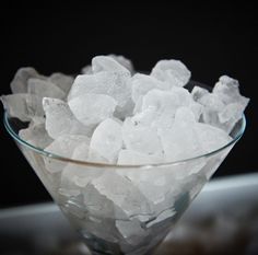 a glass bowl filled with ice cubes on top of a table