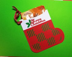 a red christmas stocking with a candy bar in the shape of a heart hanging on a green background