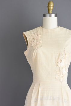 "Beautiful vintage 1950s ivory cotton day dress by Carlye. This vintage dress features fantastic floral appliqués details throughout. This vintage dress features bust darts, nipped waist and a pencil skirt. There is a back metal zipper for closure. ✂------ M E A S U R E M E N T S ------- Best Fit: XS Bust: 34\" Waist: 24\" Hips: 34.5\" Total Length: 40\" Tag/Label: Carlye Material: cotton Condition: Excellent vintage condition that is ready to wear. ☆ Layaway is available for this item! ☆ Expres 1950s Style Cream Vintage Dress, Cream 1950s Style Vintage Dress, Vintage Beige Dresses With Floral Embroidery, Fitted Cotton Dresses With Floral Applique, 1950s Style Cream Dress, Retro Cream Cotton Dress, Vintage Cream Cotton Dress, Fitted Beige Cotton Vintage Dress, 1950s Cream Dress For Vintage Fashion