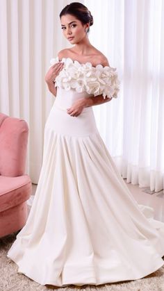 a woman in a white dress is posing for the camera with flowers on her shoulder