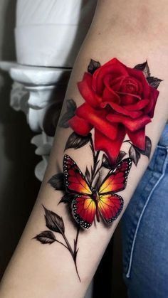 a woman with a red rose and butterfly tattoo on her arm